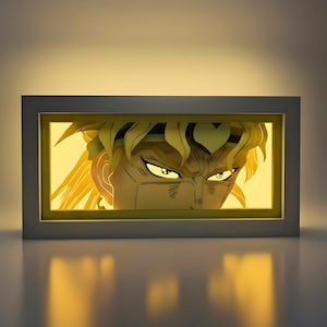 May include: A framed, illuminated artwork depicting an anime character's face. The character has spiky blonde hair, intense yellow eyes, and a determined expression. The artwork is set against a warm, yellow background, and framed in a white rectangular frame.