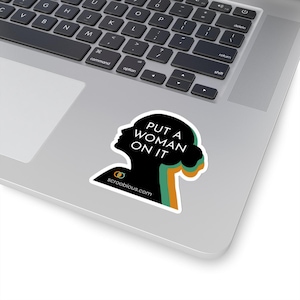May include: A black and green sticker with a silhouette of a woman's head and the text "PUT A WOMAN ON IT" and the website "scroobious.com".