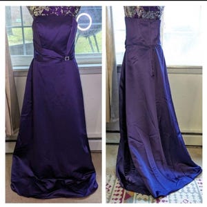 Peut inclure: Une robe de soirée longue et sans bretelles, de couleur violet profond. Le corsage présente un haut décoratif à paillettes et une taille cintrée avec une boucle argentée. La jupe tombe jusqu'au sol, créant une silhouette élégante. Parfait pour les occasions spéciales.