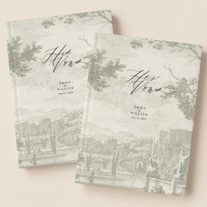 以下が含まれることがあります： 薄いグレーの風景デザインの結婚誓約書2冊。「His Vows」と「Her Vows」がエレガントな筆記体で書かれています。どちらの書籍にも「Emma & William」という名前と「June 6, 2026」という日付が記載されています。