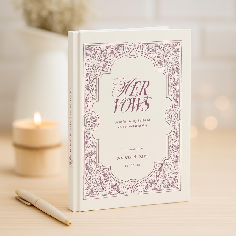 May include: A cream-colored wedding vow book with the words "Her Vows" in a decorative font. The cover features an ornate, purple border and the names "Sophia & Dave" with a date. A pen and candle are in the background.