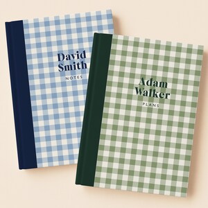 May include: Two hardcover notebooks with a gingham pattern. One is light blue with the text "David Smith NOTES" and a navy blue spine. The other is green with the text "Adam Walker PLANS" and a dark green spine.