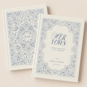 May include: Two off-white wedding vow books with blue floral designs. One book reads "HER VOWS" with the names Emma & Andrew and the wedding date. The other book has the initials "E & A".