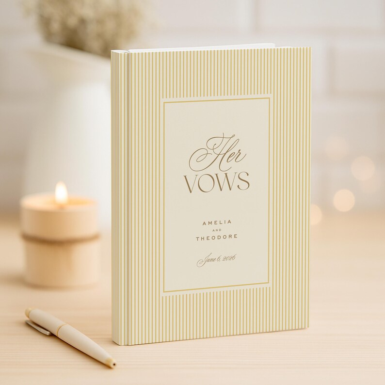 K&ouml;nnte beinhalten: Ein cremefarbenes Hochzeitsgel&uuml;bdebuch mit vertikalem Streifenmuster. Das Buch zeigt die Worte "Her Vows" in eleganter Schrift, zusammen mit den Namen Amelia und Theodore und dem Datum 6. Juni 2026. Ein Stift liegt auf dem Tisch.