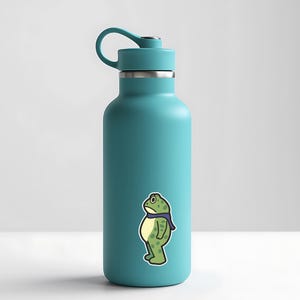 May include: A teal water bottle with a black lid and handle. A sticker of a cartoon frog wearing a purple scarf is on the front. The frog is green with yellow accents and a sad expression.