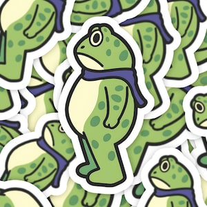May include: A collection of stickers featuring a cartoon frog with a sad expression. The frog is green with darker green spots, a light yellow belly, and a blue scarf. The stickers have a white border.
