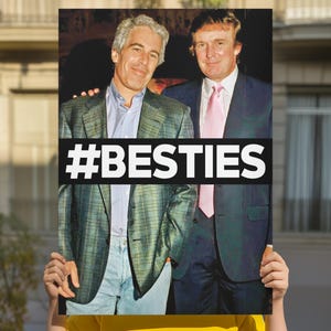 Może przedstawiać: Osoba trzymająca plakat ze zdjęciem dwóch mężczyzn. Na plakacie widnieje napis „#BESTIES” dużymi białymi literami. Tło to budynek z oknami i balkonem.