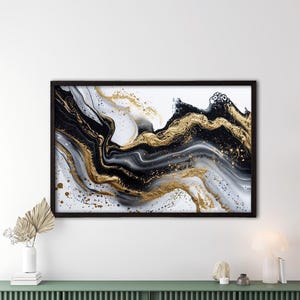 Può includere: Stampa artistica astratta in una cornice nera. L'opera presenta un design fluido con colori neri, bianchi e oro. La stampa è esposta sopra un mobile verde in un ambiente moderno.