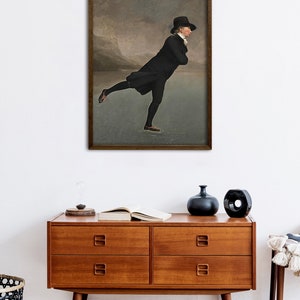 May include: A painting of a man in a black coat and top hat ice skating on a frozen lake. The background is a cloudy sky with mountains in the distance.