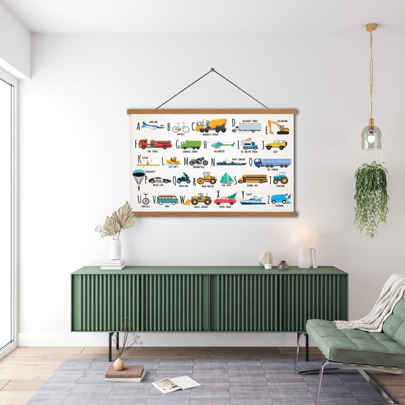 Puede incluir: Un gr&aacute;fico de alfabeto colorido con ilustraciones de diferentes veh&iacute;culos para cada letra. El gr&aacute;fico est&aacute; enmarcado en madera y cuelga de una pared blanca.