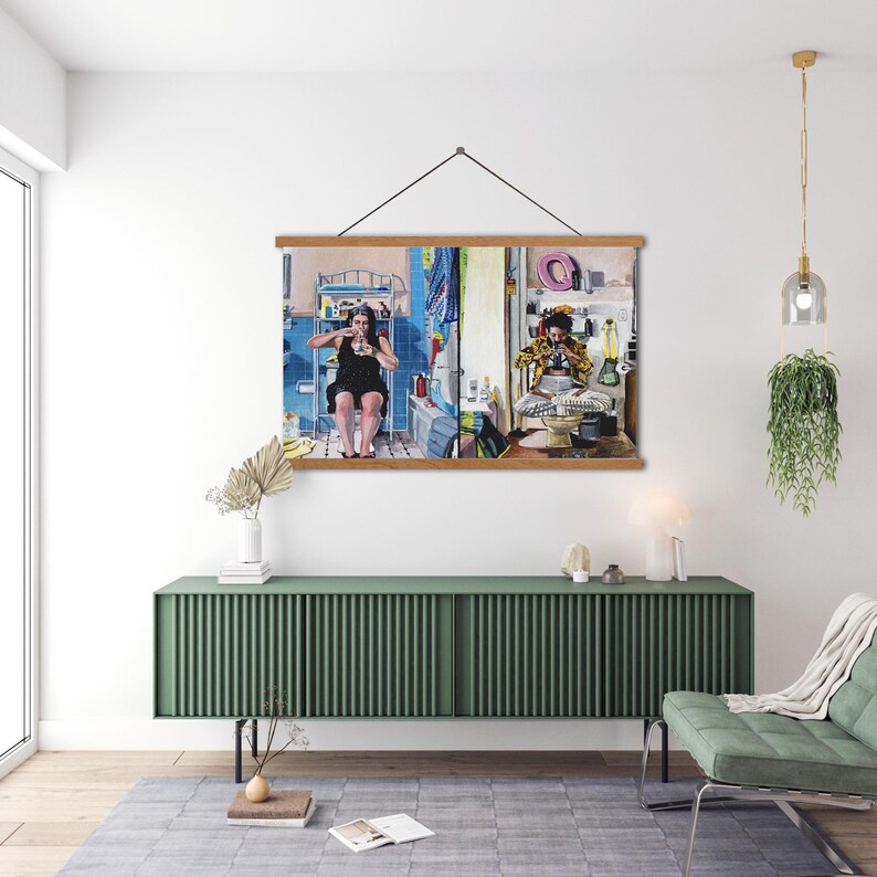 May include: A framed print of a split-screen image showing two people in separate rooms. The person on the left is wearing a black dress and is sitting on a toilet. The person on the right is wearing a yellow and black patterned shirt and is sitting on a toilet. The print is hanging on a green wall above a green cabinet.