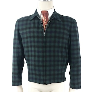 May include: A green and black checked jacket with a full zip. The jacket features a collared neckline and long sleeves. A patterned tie is visible beneath the zip.