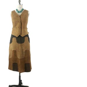 May include: A brown suede vest and skirt set with a geometric pattern. The vest has a button closure and the skirt is knee-length.