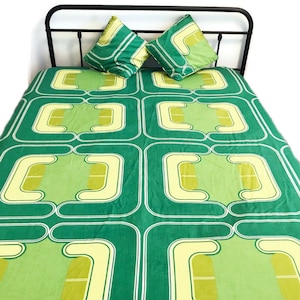 Peut inclure: Une housse de couette à motifs géométriques verts et jaunes avec deux taies d'oreiller assorties. La housse de couette présente un motif répétitif de carrés aux coins arrondis et un design de lignes courbes.