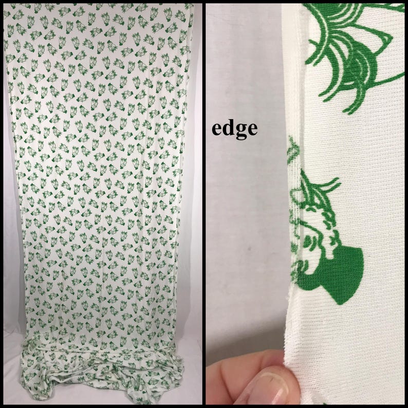May include: White fabric featuring a repeating pattern of green floral designs. The fabric is draped, displaying the pattern's coverage. A close-up shows the fabric's edge, highlighting the material's texture and the green floral design.
