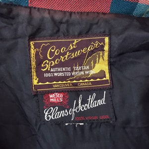 以下が含まれることがあります： 2 つの生地ラベルのクローズアップ。上部のラベルには「Coast Sportswear AUTHENTIC TARTAN 100% WORSTED VIRGIN WOOL」と書かれており、その下に「Vancouver, Canada」と書かれています。下部のラベルには「Wesco Mills Clans of Scotland 100% VIRGIN WOOL」と書かれています。