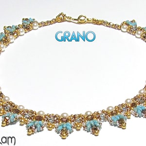Puede incluir: Un collar de cuentas doradas y turquesas con perlas blancas. El collar tiene un diseño delicado e intrincado y está acentuado con pequeñas cuentas doradas. El collar está etiquetado como "GRANO".