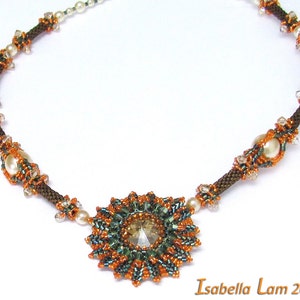 Könnte beinhalten: Eine braune und grüne Perlenkette mit einem großen, glitzernden Kristall als Mittelstück. Die Kette ist mit kleinen weißen Perlen und braunen Perlen verziert.