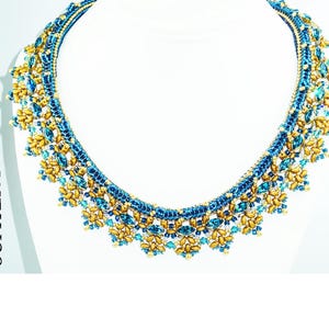 Puede incluir: Un collar de cuentas doradas y azules con un diseño floral. El collar se llama "JUPITER P84B".