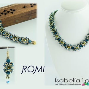 May include: Jewelry set featuring a necklace, bracelet, and earrings. The pieces are adorned with teal and gold-colored beads. The necklace is displayed on a white mannequin. The bracelet and earrings are displayed on a wooden box. The brand name "ROMI" is visible.