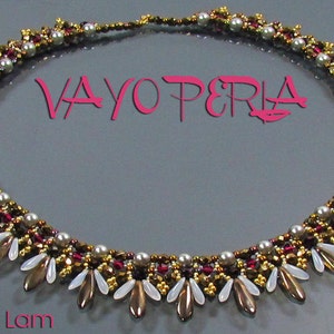 May include: A gold and burgundy beaded necklace with white and gold teardrop-shaped beads. The necklace is on a gray surface and has the text "VAYO PERLA" in pink letters.