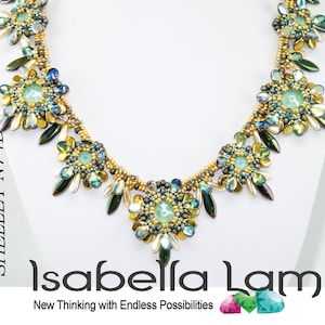Puede incluir: Un collar de cuentas doradas y verdes con un diseño floral. El collar está hecho con cuentas iridiscentes y presenta una flor central con un centro verde claro. El collar está etiquetado como "SHELLEY N74D" e "Isabella Lam New Thinking with Endless Possibilities".