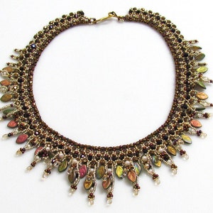 May include: A brown and gold beaded necklace with a leaf design. The necklace has a gold clasp and is accented with iridescent beads.