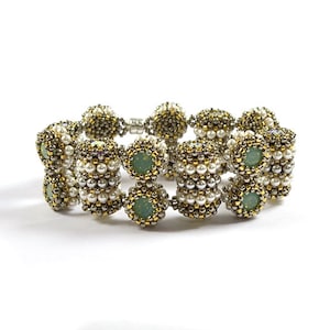 May include: A beaded bracelet with a silver and gold finish. The bracelet features green gemstone accents and white pearl-like beads.