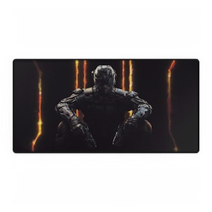 May include: Black rectangular gaming mouse mat featuring a futuristic armored figure in a crouching position. The figure is dark grey with intricate details, set against a black background with vertical orange streaks.