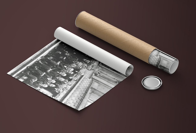 Puede incluir: Una impresi&oacute;n fotogr&aacute;fica en blanco y negro, parcialmente desenrollada, que representa a un grupo de personas. La impresi&oacute;n va acompa&ntilde;ada de un tubo blanco enrollado, un tubo de cart&oacute;n marr&oacute;n y una tapa plateada. La fotograf&iacute;a est&aacute; sobre una superficie marr&oacute;n oscuro.