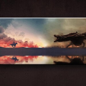 May include: A silhouette of a rider on horseback facing a large, dark dragon with red and orange clouds in the background. The dragon is facing the rider and has its mouth open. The scene is reflected in a body of water in the foreground.