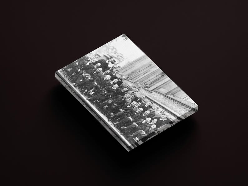 Puede incluir: Fotograf&iacute;a en blanco y negro de un grupo de hombres con trajes y sombreros, probablemente de principios del siglo XX. La imagen est&aacute; impresa sobre una superficie rectangular y brillante, sobre un fondo oscuro.