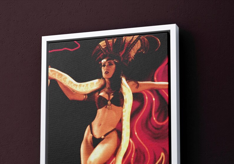 May include: A woman wearing a red and black costume with a snake wrapped around her body. She is posing in front of a red and white background.