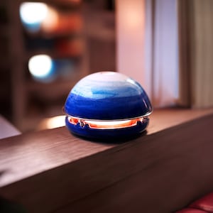 Könnte beinhalten: Ein blauer und weißer Keramikdiffusor mit silbernem Rand. Der Diffusor ist beleuchtet und hat einen warmen Schein.