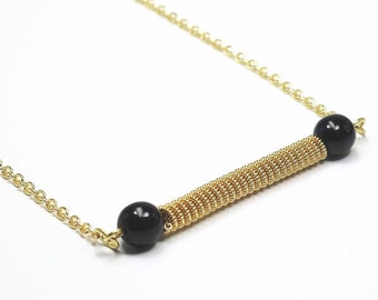 Peut inclure: Un collier en chaîne dorée avec une bobine de fil doré et deux perles noires.