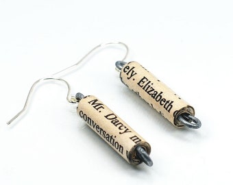 May include: A pair of silver dangle earrings with rolled paper charms. The charms are made from book pages and feature the text "Mr. Darcy" and "Elizabeth" in black ink.