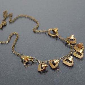 May include: A gold chain necklace with multiple small, dangling charms in the shape of a key. The charms are attached to the chain with small rings.