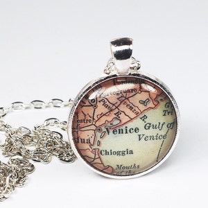 May include: A silver necklace with a round pendant featuring a vintage map of Venice, Italy. The map shows the city's canals, islands, and surrounding areas. The pendant is about 1 inch in diameter.