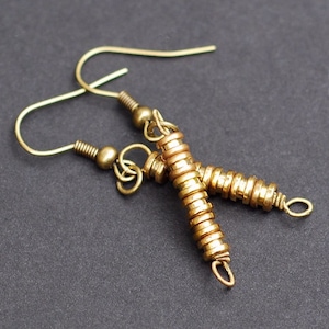 May include: A pair of gold-toned earrings with a long, stacked, cylindrical design. Each earring is made of multiple small, round, metal beads.