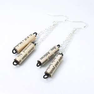 May include: A pair of silver chain earrings with three small paper scroll charms. The charms are made from recycled book pages and feature text from "To Kill a Mockingbird".