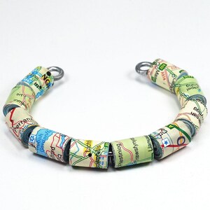 May include: A bracelet made of rolled up maps with silver clasps. The maps feature place names like "Perran", "Frebah GardenH", "Ffestiniog", and "Trawsfynydd".