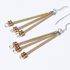 May include: A pair of gold earrings with three dangling springy strands. Each strand has a small gold bead at the end.