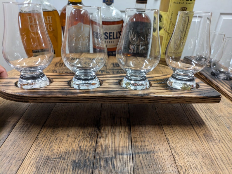 Puede incluir: Una bandeja de servir de madera con cuatro ranuras para vasos. La bandeja est&aacute; hecha de madera reciclada y tiene un acabado marr&oacute;n oscuro. La bandeja es perfecta para servir bebidas o aperitivos.