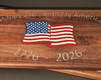 Puede incluir: Tabla de cortar rectangular de madera con el texto "Happy 250th Birthday America" y los años "1776 - 2026" grabados. La bandera americana está en el centro, con rayas rojas y blancas y un campo azul de estrellas.