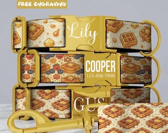Puede incluir: Tres collares para mascotas con hebillas y herrajes de metal dorado. La tela presenta un patrón repetitivo de gofres y fresas. Las hebillas están grabadas con los nombres Lily, COOPER y GUS, con un número de teléfono en la hebilla central.