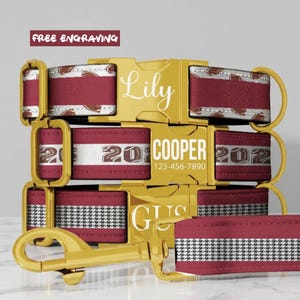 May include: Three pet collars and a leash featuring maroon fabric with white and black patterns. Each collar has a gold-toned metal buckle engraved with names like Lily, Cooper, and Gus, along with a phone number on the center buckle.