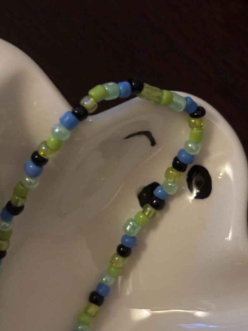 K&ouml;nnte beinhalten: Ein Armband mit schwarzen, blauen und gr&uuml;nen Perlen.