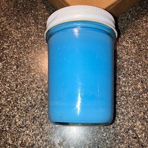 Peut inclure: Un bocal en verre avec un couvercle blanc rempli d'une bougie bleu vif.