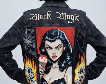 May include: Black denim jacket with a hand-painted design featuring the words "Black Magic" in gold lettering. The back of the jacket showcases a retro comic-style illustration of a woman holding an ice cream cone, with skulls and flames.