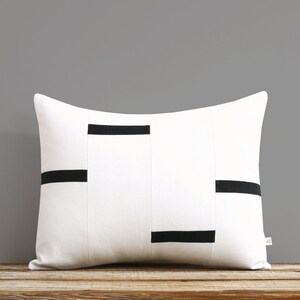 May include: White rectangular pillow with black horizontal stripes. The pillow is made of a soft, textured fabric.